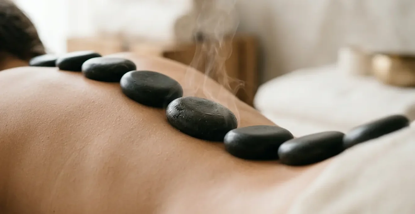 Massage aux pierres chaudes sur le dos avec vue des pierres de basalte lisses et vapeur diffuse