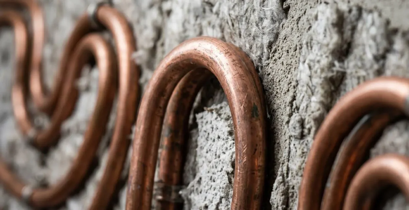 Détail macro de tuyaux de chauffage installés en serpentin dans un mur de hammam avant carrelage